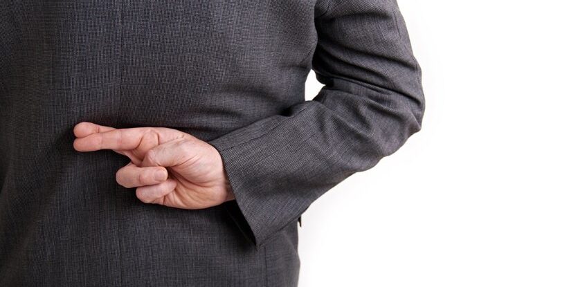 business man with his fingers crossed behind his back.