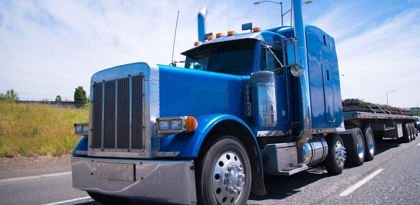 blue tractor trailer traveling down highway