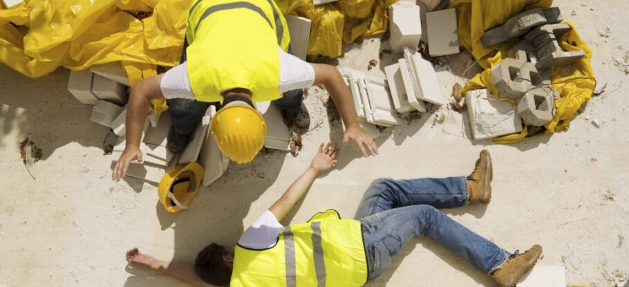 construction worker on ground unconscious with coworker trying to help