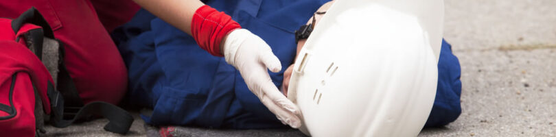 worker in white hardhat laying concrete with another worker checking to see if they are injured
