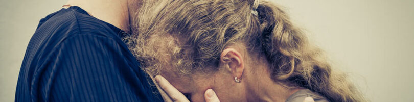 women crying into mens shoulder in grief over loss