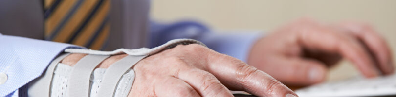 worker with cast on wrist operating keyboard mouse