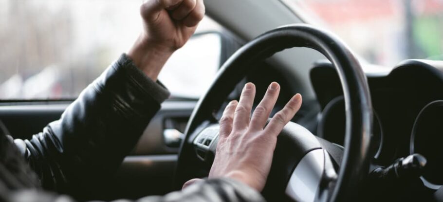 driver honking car horn with raised fist in the air