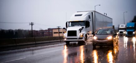 car riding beside 18-wheeler on wet highway due to rain