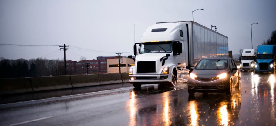 car riding beside 18-wheeler on wet highway due to rain