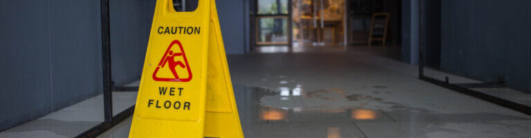 slip and fall sign near a liquid spill in hallway