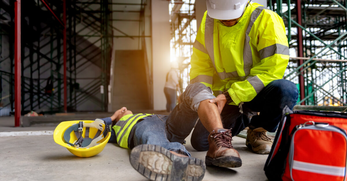 Trabajador de la construcción ayudando a otro trabajador herido en el suelo