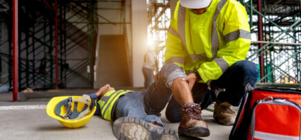Trabajador de la construcción ayudando a otro trabajador herido en el suelo