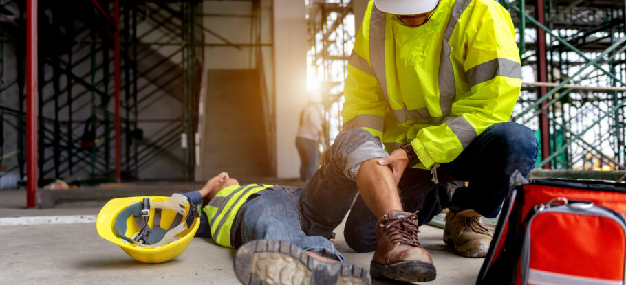Trabajador de la construcción ayudando a otro trabajador herido en el suelo