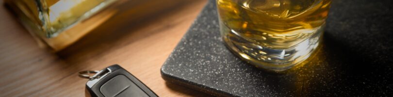 set of car keys sitting beside an alcoholic beverage on a bar