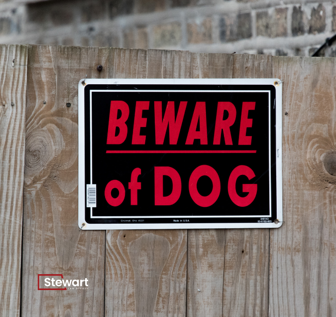 beware of dog sign on wooden fence with Stewart Law Offices logo
